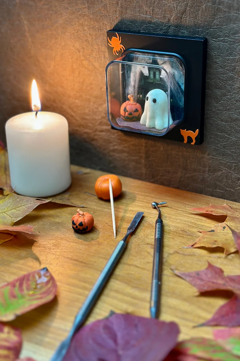 miarama-Element mit selbst modelliertem Gespenst und Kürbis, davor eine brennende Kerze, Mini-Kürbisse und Herbstlaub